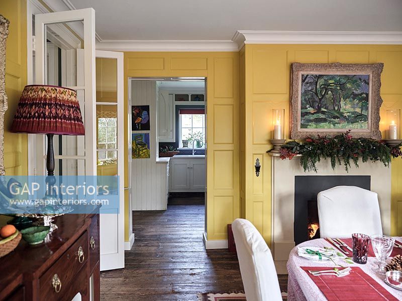View into kitchen from yellow painted panelled dining room 