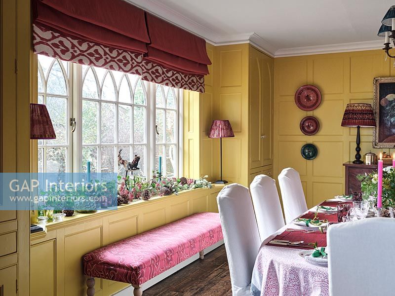 Pink seat next to window in classic dining room decorated for Christmas 