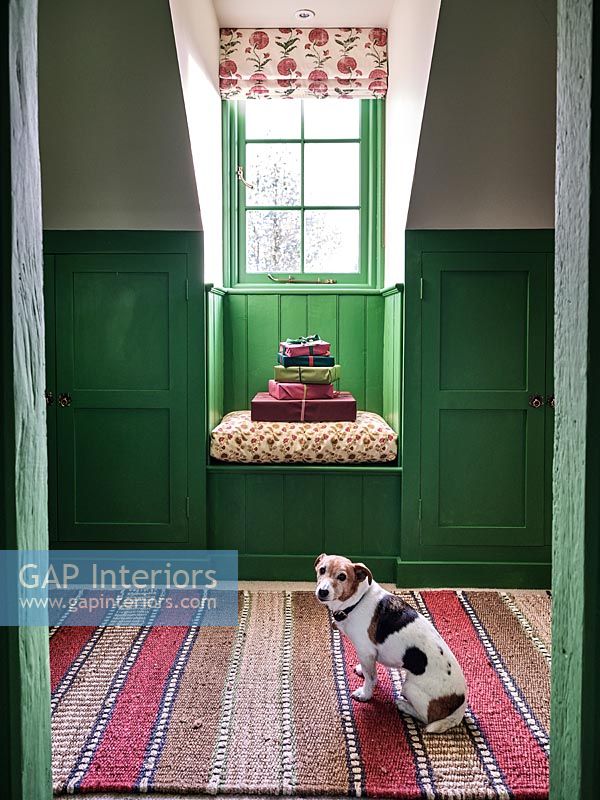 Wrapped gifts on tiny window seat with green painted panelled walls 