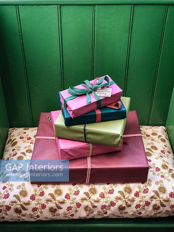 Wrapped gifts on tiny window seat with green painted panelled wall