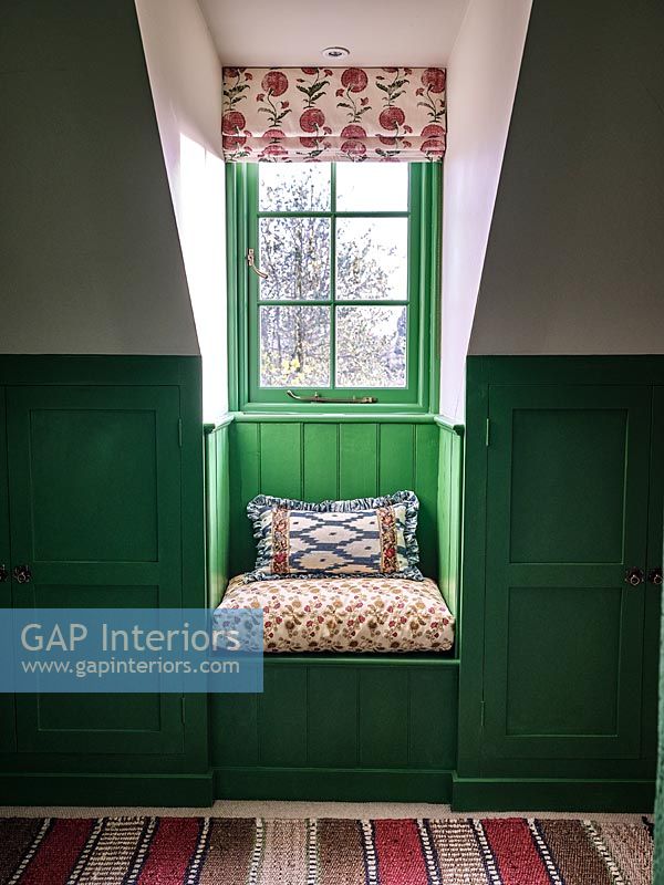 Tiny window seat with green painted panelled wall