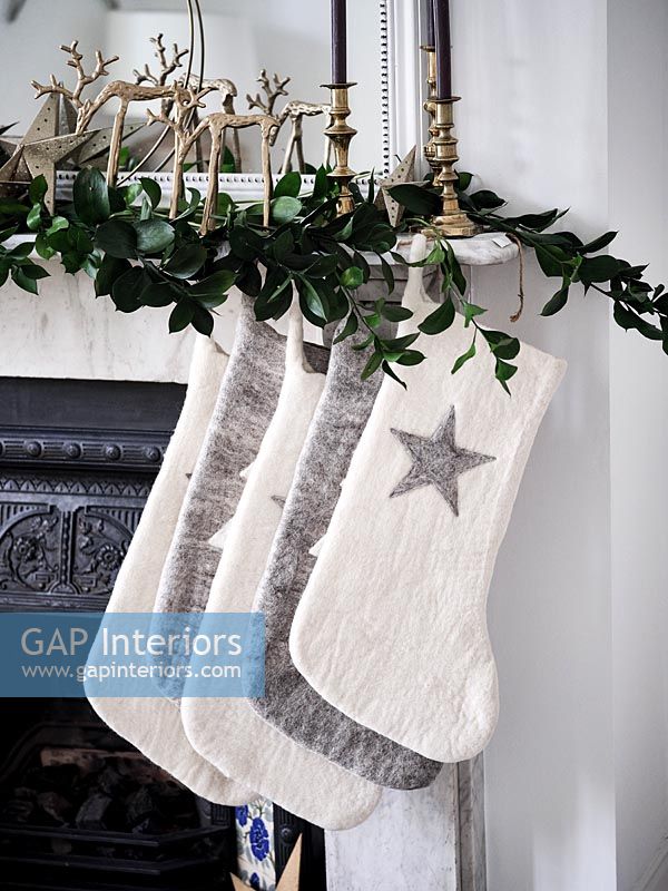 Cream and grey Christmas stockings hanging on mantelpiece 