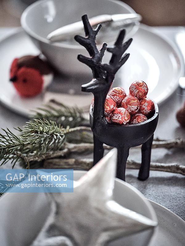 Chocolates in small reindeer ornament on dining table 