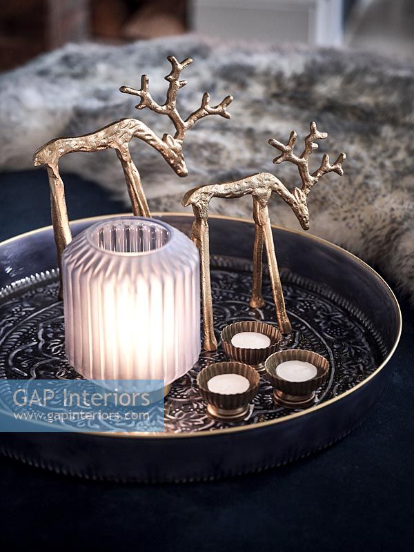 Gold reindeer ornaments next to lantern 