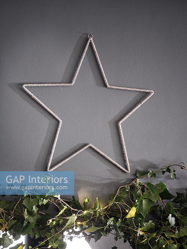 Silver star against grey painted wall with ivy garland Christmas decoration