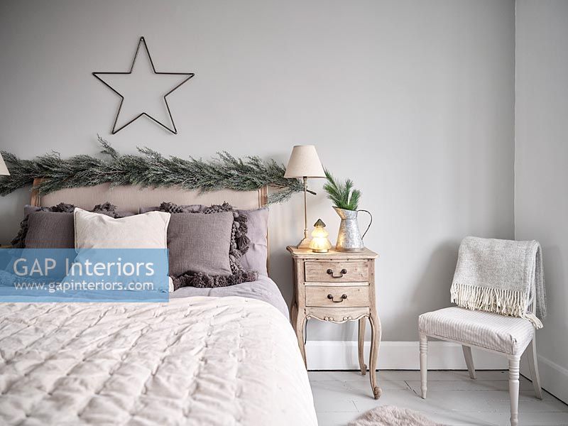 Garland and star above headboard in modern bedroom 