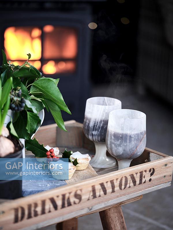 Mince pies and drinks on tray with lit fire behind 
