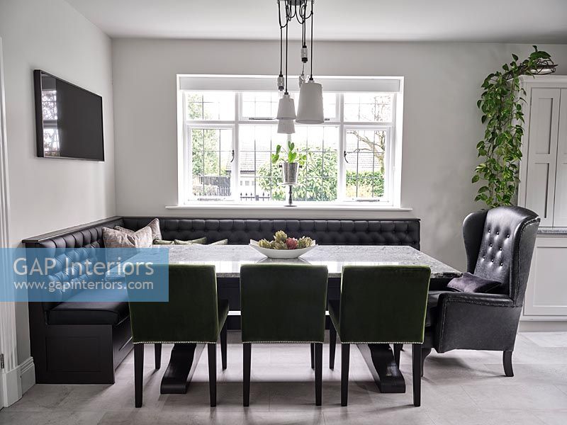 Upholstered corner bench and leather armchair seating in modern dining room