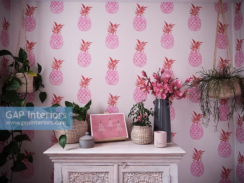 Painted unit and houseplants in bathroom with pink pineapple wallpaper 