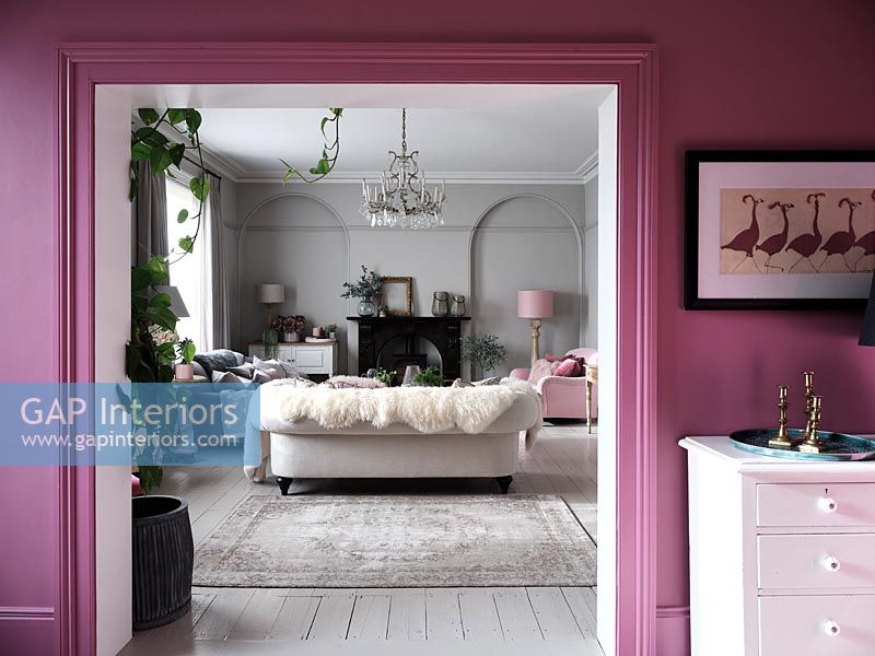 Pink painted wall with view into modern living room 