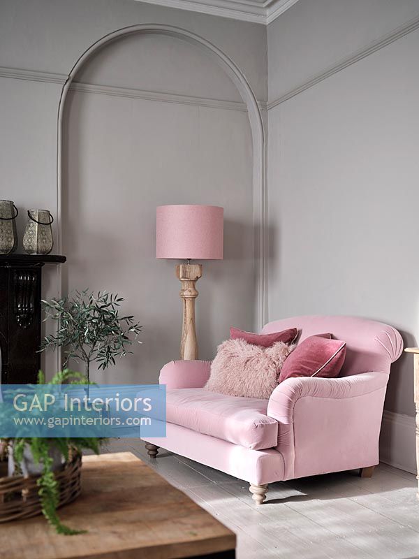 Pink sofa and floor lamp next to grey painted wall 