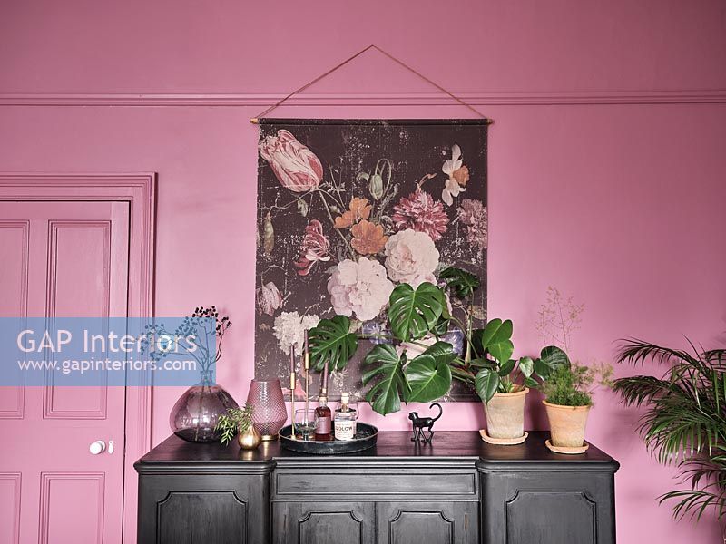 Black painted wooden sideboard next to pink wall 