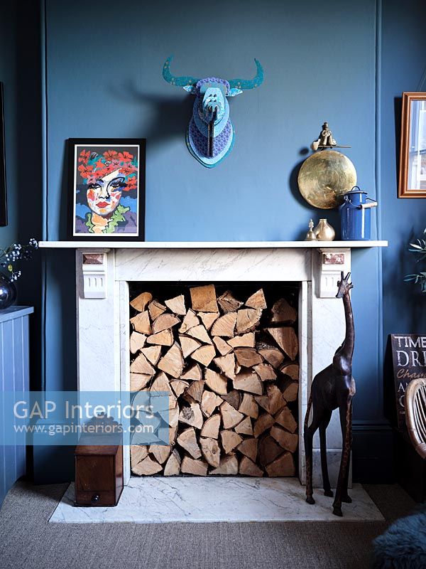 Fireplace filled with logs in modern blue painted living room 