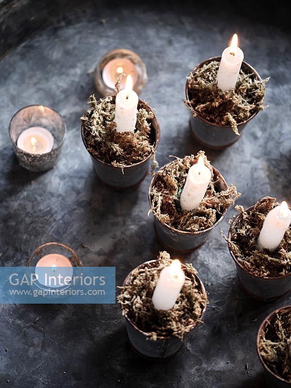 Lit candles in tiny pots with decorative moss 