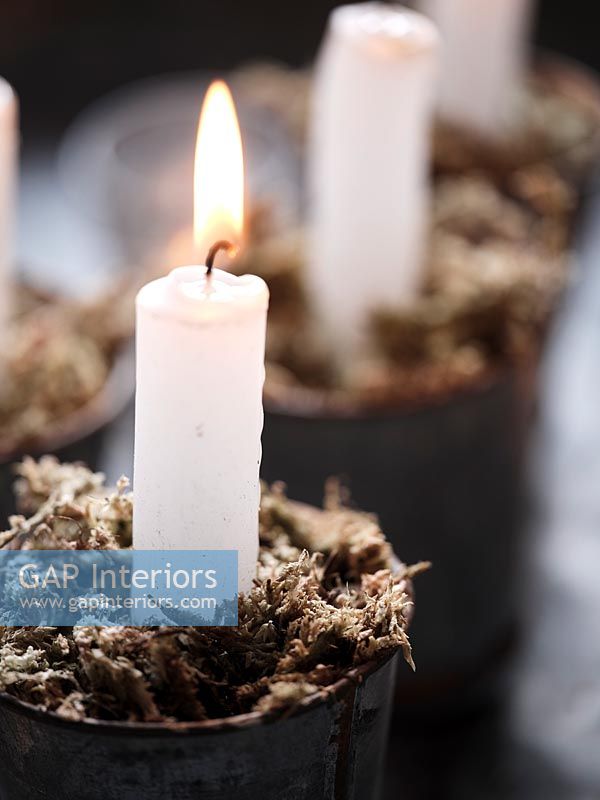 Lit candle in tiny pots with decorative moss 