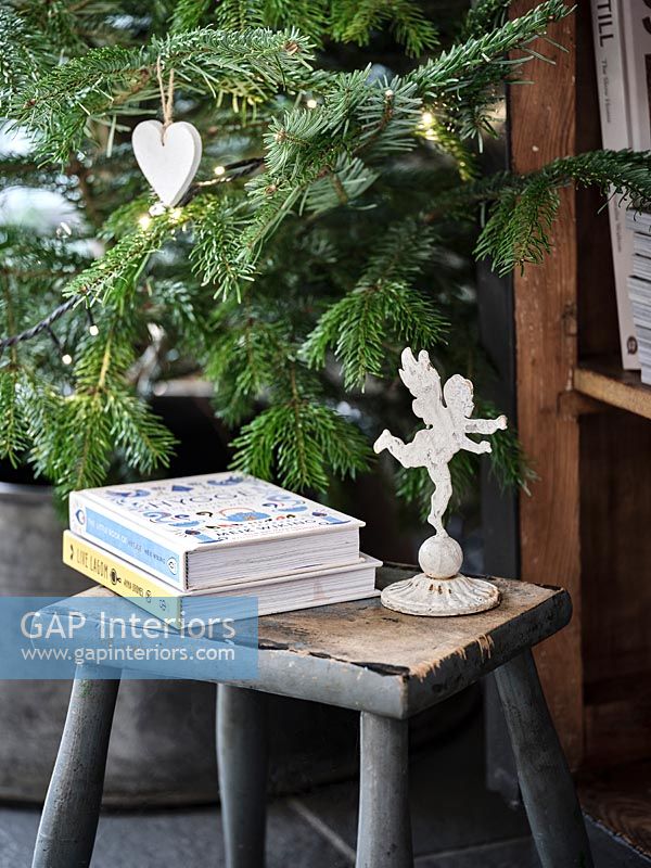 Books and angel ornament next to Christmas tree 