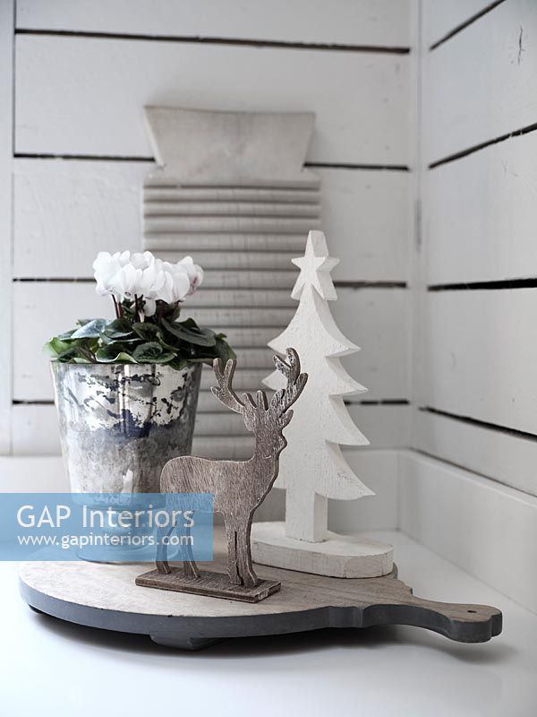 Carved reindeer ornament and white cyclamen in pot 