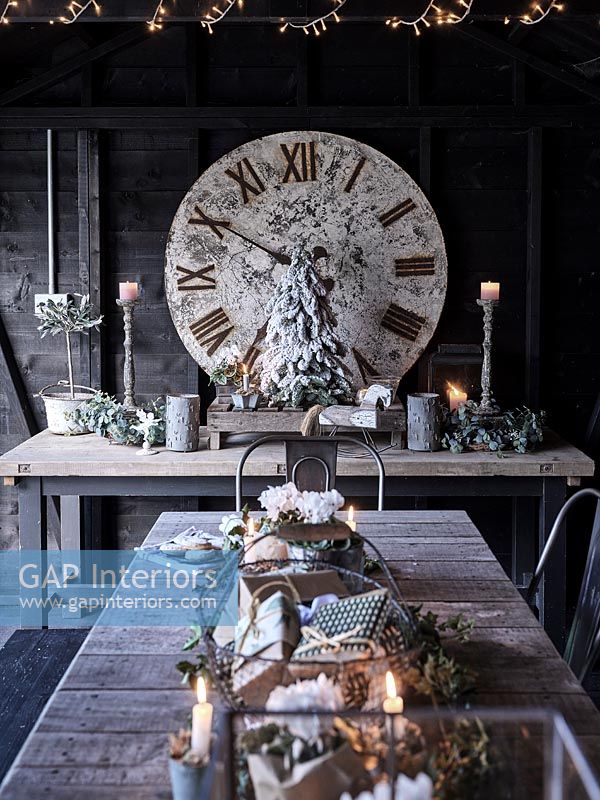 Large clock, Christmas decorations and lights around table 