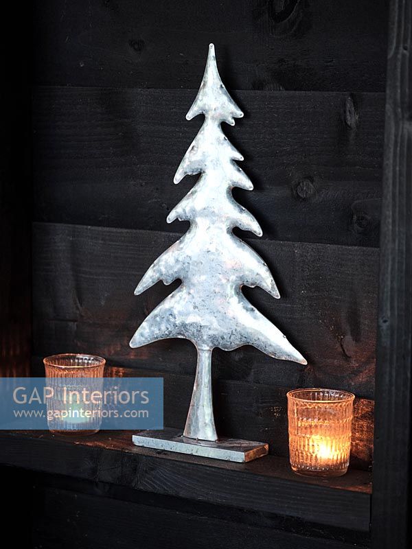 Silver tree ornament flanked by tealight candles 