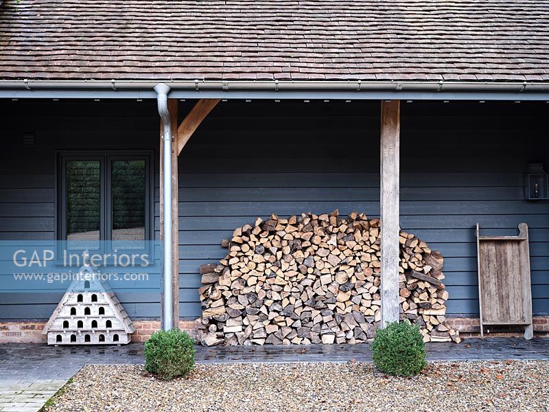 Large woodpile on covered terrace of country house 