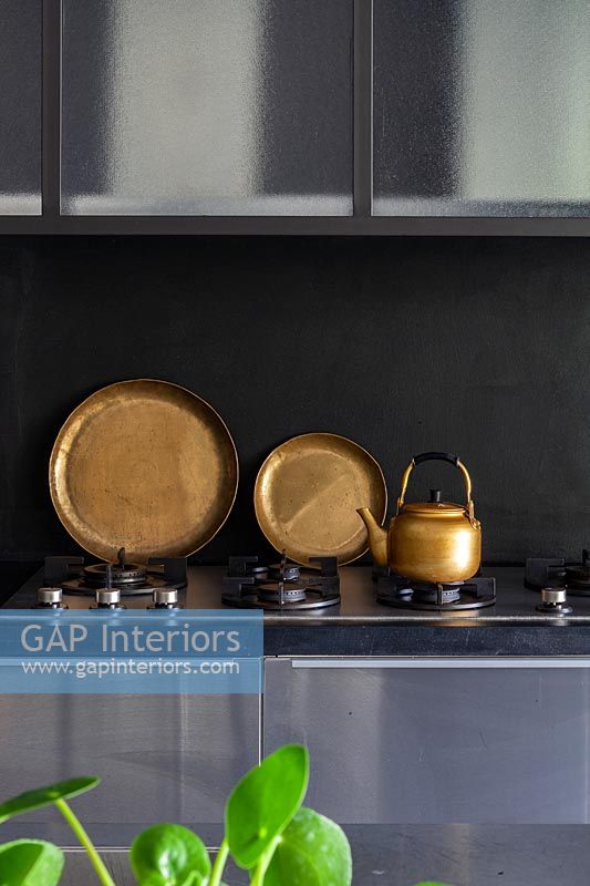 Black gas hob with decorative copper plates and kettle 