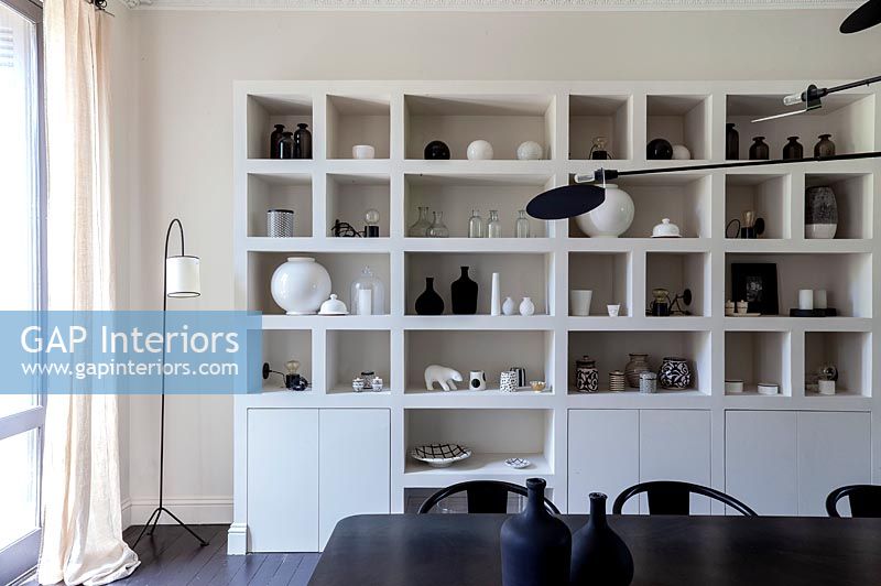 Black and white ceramics displayed on large unit in modern dining room 