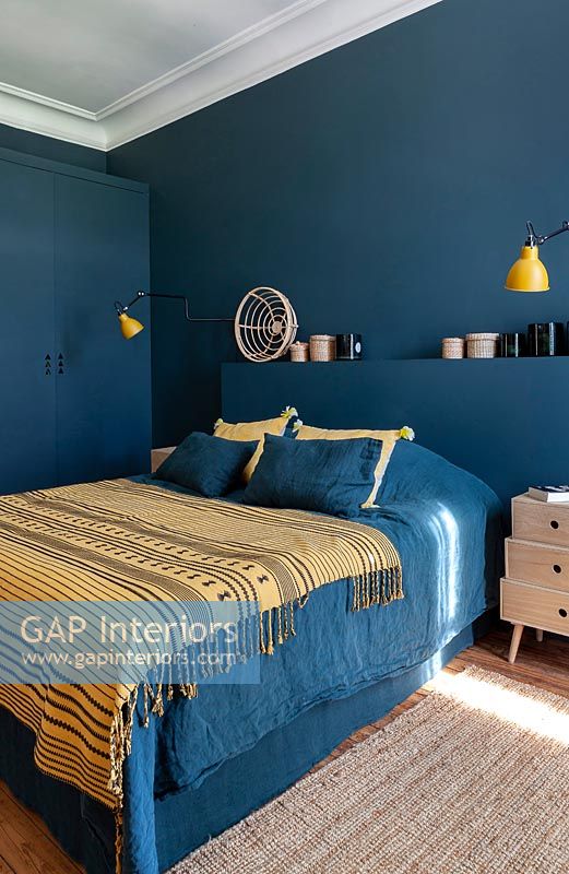 Dark blue painted walls and headboard in modern bedroom 