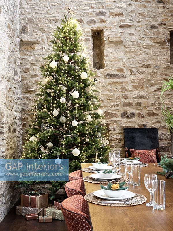 Country dining room with exposed stone walls decorated for Christmas 