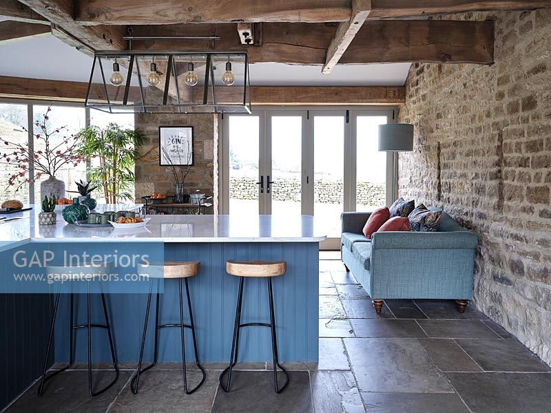 Modern blue kitchen with exposed wooden beams and stone wall 