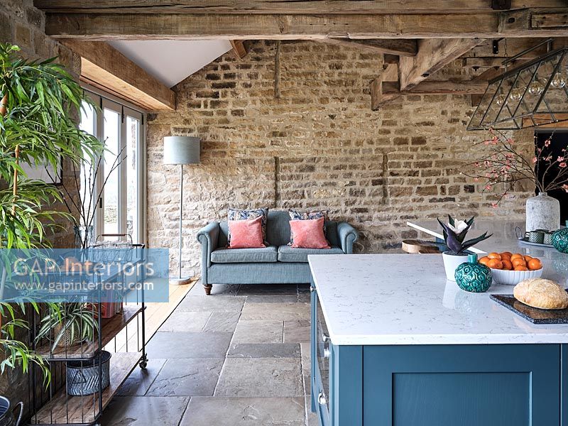 Sofa next to exposed stone wall in modern country kitchen 