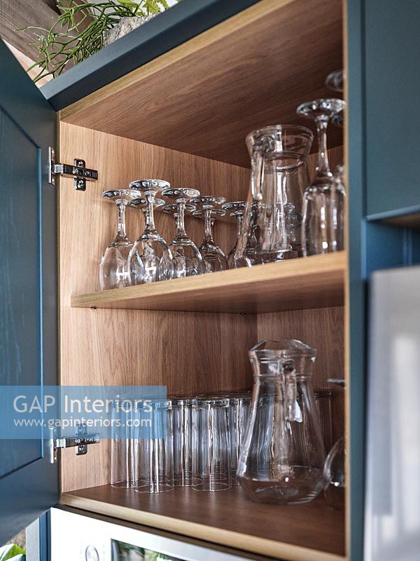 Open kitchen cabinet door with shelves of glasses 
