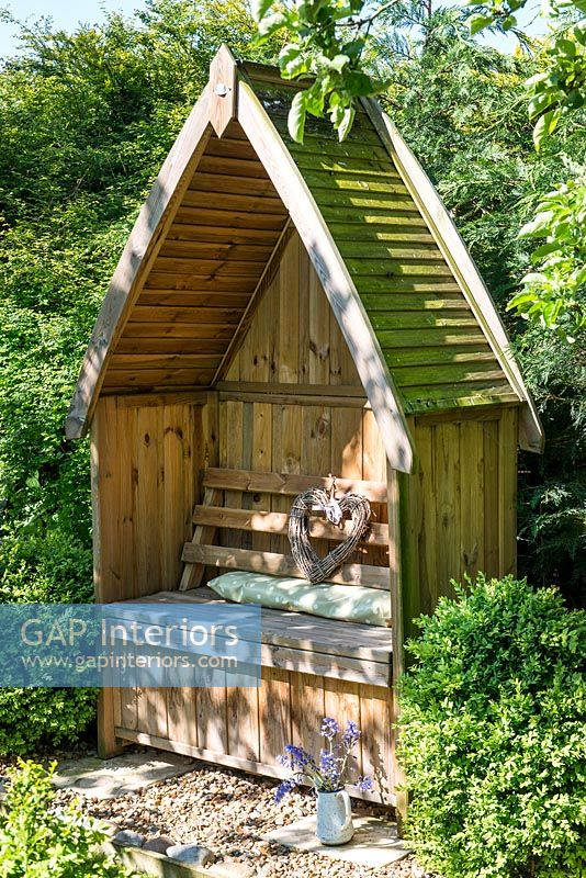 Decorative wooden arbour seat in country garden 