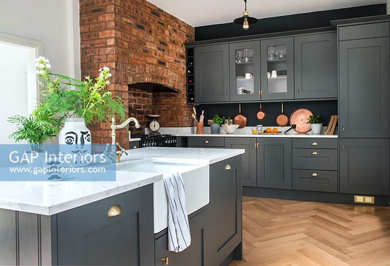 Dark grey modern kitchen with exposed brick wall and parquet flooring 