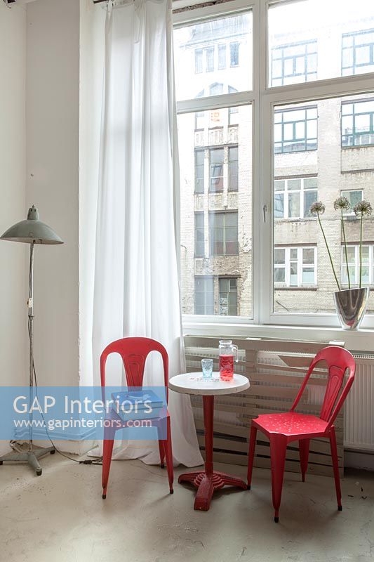 Bright red chairs and small side table next to window 