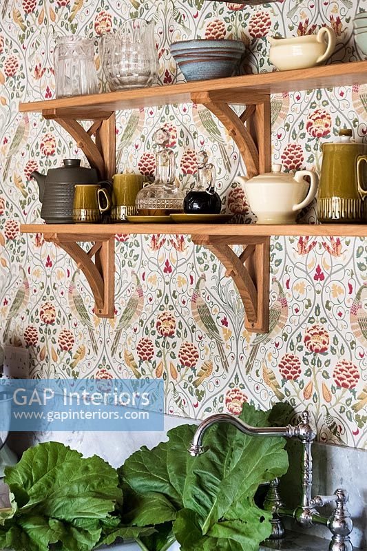 Patterned wallpaper and wooden shelves in kitchen 