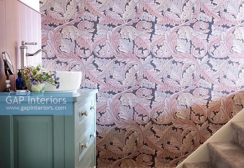 Pink patterned wallpaper next to green sink unit 