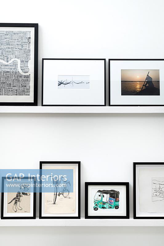 Display of black framed pictures on white shelves 