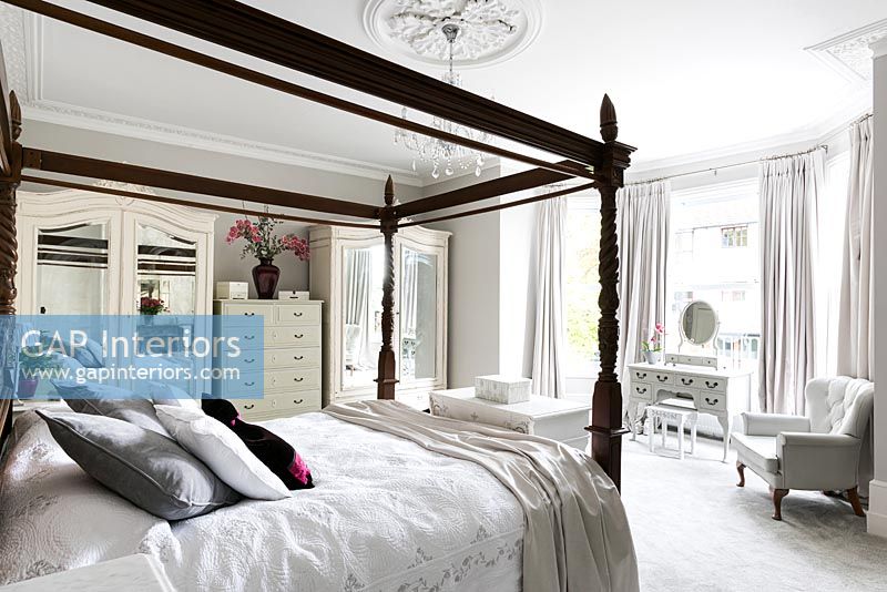 Black fourposter bed in white bedroom 