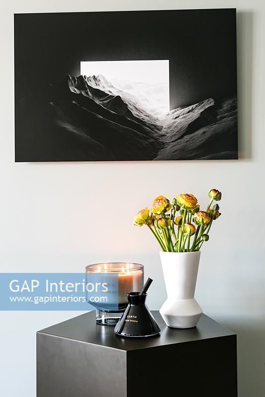 Flowers on side table with black and white picture above 