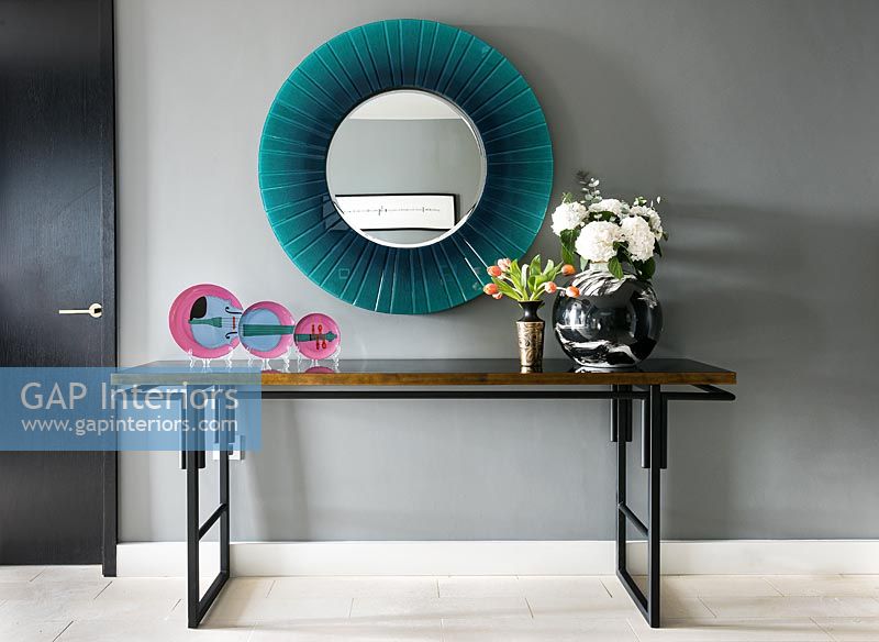 Display of decorative plates and flowers on modern console table 
