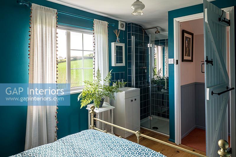 Colourful country bedroom with brass bed and shower cubicle 