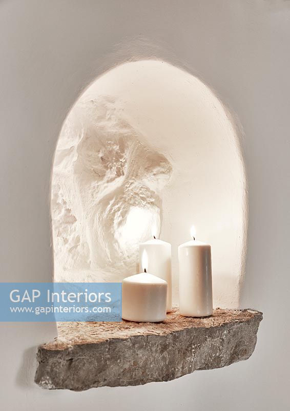 Candles in white wall alcove with stone shelf