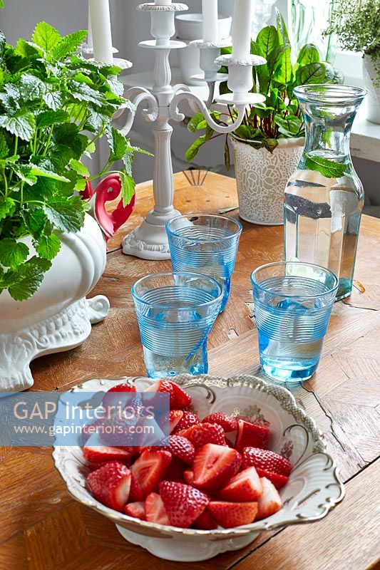Bowl of strawberries and glasses of water on wooden table 