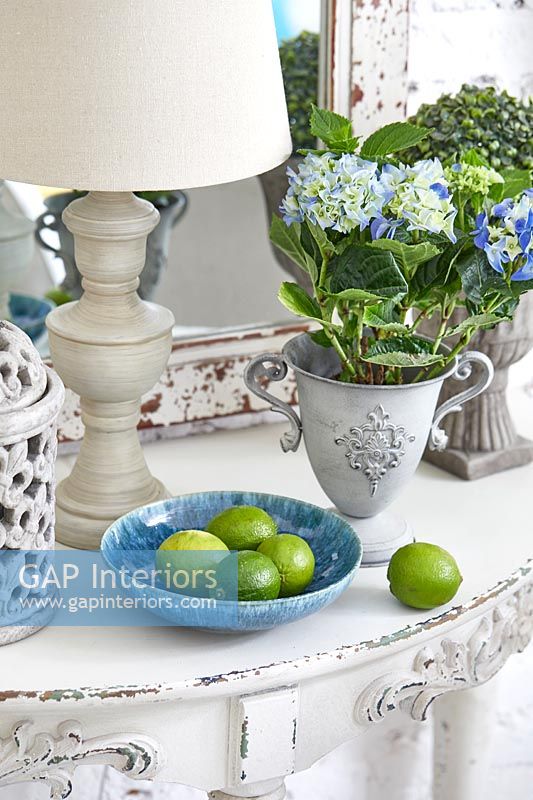 Detail of blue fruit bowl and houseplants on shabby chic console table 