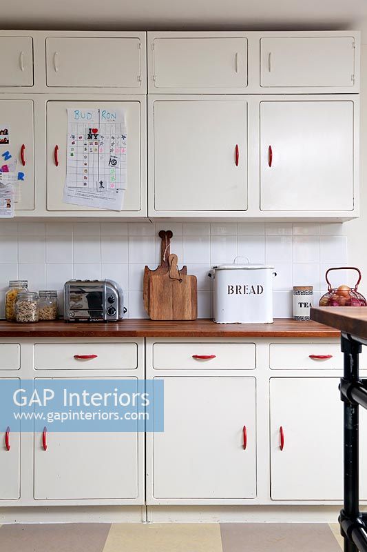 White kitchen cabinets with red handles in modern kitchen 