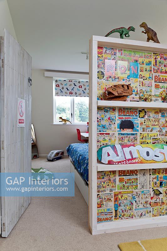 Bookcase lined with pages of colourful kids comics in childrens bedroom 