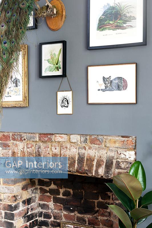 Display of framed artwork on grey painted wall above fireplace 