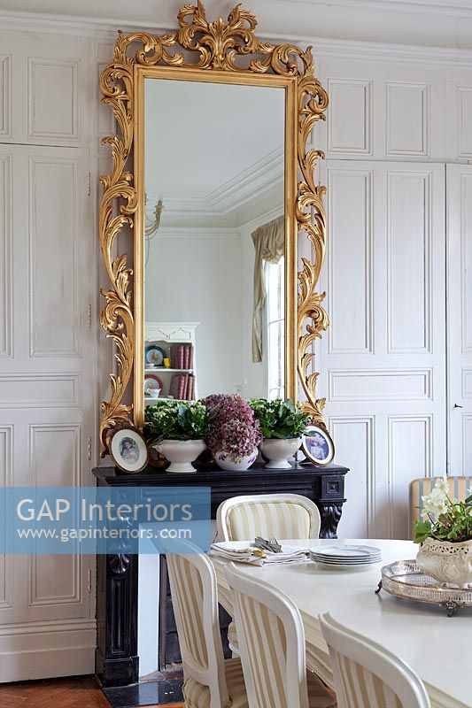 Gilded mirror on panelled wall in classic dining room 