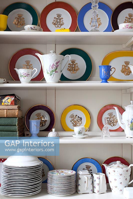 Colourful display of plates and crockery on dresser shelves 