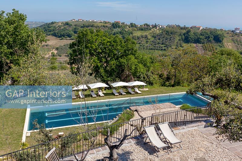 View of swimming pool with rows of loungers and scenic views beyond 